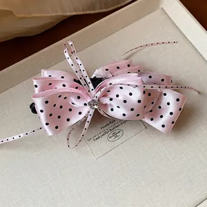 Barrette à cheveux élégante à pois roses avec nœud et strass présentée sur un plateau