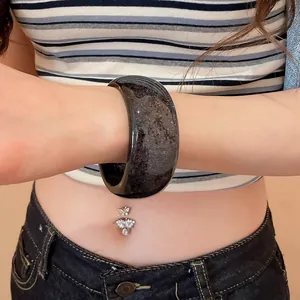 Detailed view of a wide resin bangle featuring colorful sequins on a female wrist