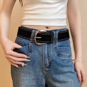 Detail view of a stylish black leather belt with a silver metal buckle worn on blue denim jeans