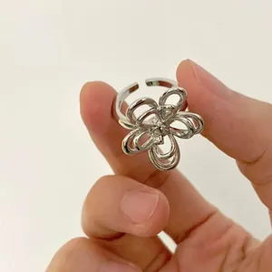Close-up of a silver-colored layered wire flower ring with crystals held by a hand