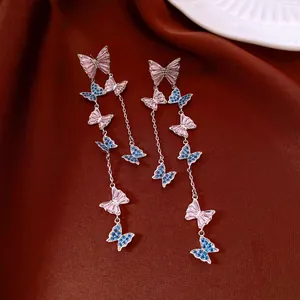 Detailed view of long butterfly tassel earrings with pink and blue zircons and silver finish.