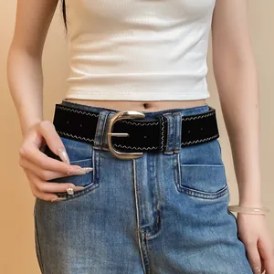 Detail view of a black leather belt with silver buckle and white zigzag stitching