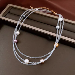 Close-up of elegant multi-layered crystal and colorful pearl beaded necklace on brown gift box