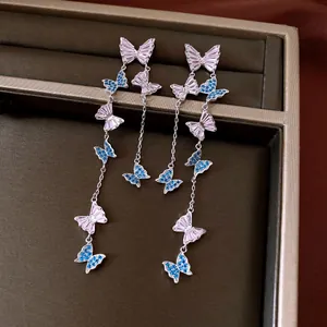 Detailed macro view of silver needle tassel earrings featuring pink and blue zircon butterflies
