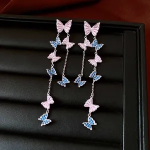 Close-up of elegant long butterfly tassel earrings with pink and blue zircons.