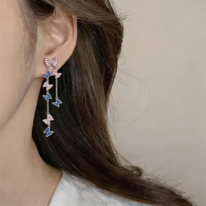 Detailed view of elegant butterfly tassel earrings featuring pink and blue accents on a model