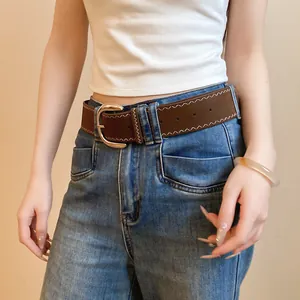 Detailed shot of a brown leather belt with a stylish metal buckle and white stitching