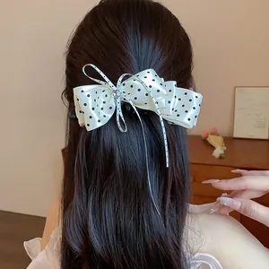 Détail de vue arrière montrant une élégante barrette à nœud blanc à pois sur cheveux longs