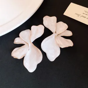 Close-up detail of elegant pale pink flower stud earrings with a polished gold trim
