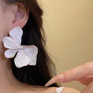 Close-up of a French vintage white enamel flower stud earring with iridescent finish