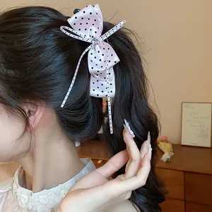 Vue rapprochée détaillée d'un nœud à cheveux rose à pois pour un coiffage élégant