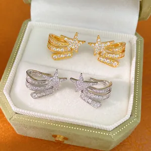 Close-up of gold and silver shooting star clip-on earrings in a green velvet box