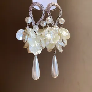 Detail showing silver needle earrings with shimmering zirconia, pearls and delicate white petals