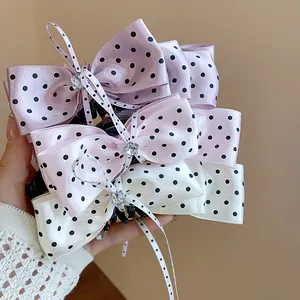 Gros plan de pinces à cheveux élégantes avec des nœuds en satin à pois et des détails en strass.