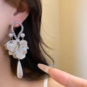 Detailed view of elegant drop earrings with pearls and white flower petals on model