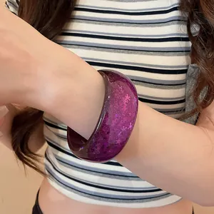 Detail shot of a stylish purple resin bangle bracelet with sparkling sequins on a model's wrist