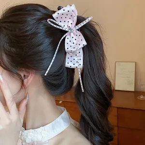 Détail d'une barrette nœud rose à pois élégante portée sur une queue de cheval brune