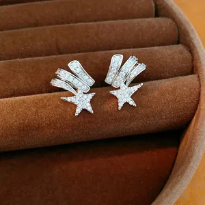 Macro detail of zircon-encrusted shooting star ear clips on a brown velvet tray