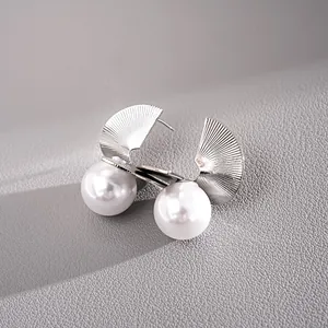 Detail view of silver metal fan-shaped stud earrings with large white pearls