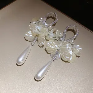 Macro view of zircon encrusted petal earrings with elegant teardrop pearls