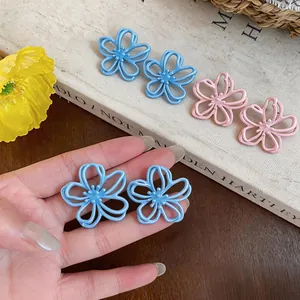 Dettaglio degli orecchini a fiore cavo blu e rosa freschi con aghi d'argento per donne