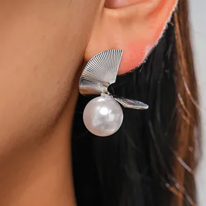 Close-up detail of silver geometric fan-shaped earring with a large white pearl