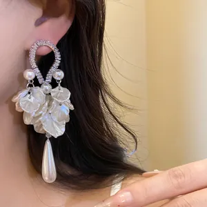 Close-up detail of elegant white petal and teardrop pearl drop earring worn on model's ear
