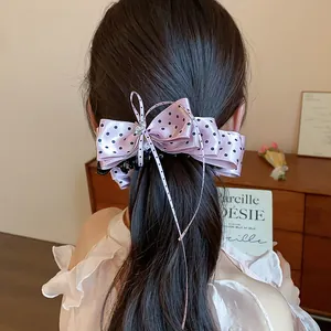 Pince à cheveux nœud rose à pois de style coréen sur la queue de cheval d'un modèle