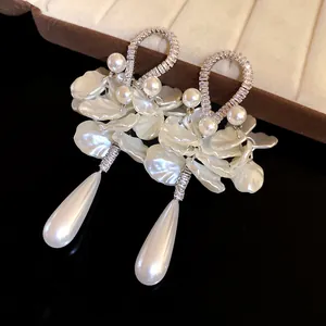 Close-up of elegant zirconia pearl earrings with white petal and teardrop pendant details.