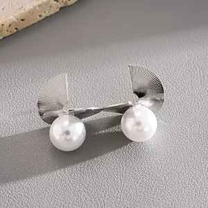 Detailed view of silver-toned geometric fan stud earrings with large white pearls