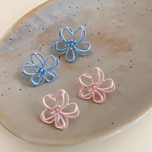 Primo piano di orecchini a forma di fiore smaltati traforati in blu e rosa pastello.