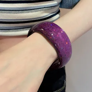 Detail view of a stylish purple resin bangle featuring sparkling glitter and shiny sequins
