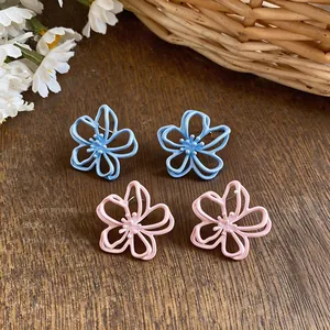 Primo piano dei piccoli orecchini a lobo smaltati a forma di fiore azzurro e rosa