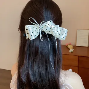 Vue rapprochée d'une pince à cheveux élégante avec un nœud à pois crème sur cheveux
