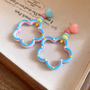 Close-up of colorful dopamine-style hollow flower earrings with heart beads