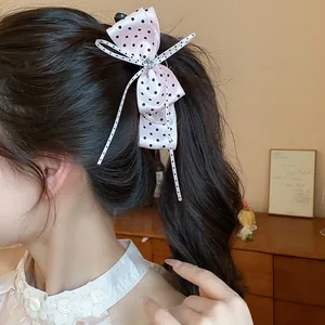 Détail d'une pince à cheveux nœud rose à pois avec décoration centrale en strass