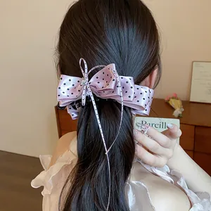 Vue détaillée d'une élégante pince à cheveux à nœud rose à pois sur une queue de cheval