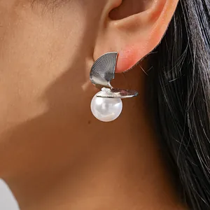 Detailed macro view of geometric silver disc earrings with elegant white pearl drop