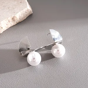 Close-up detail of silver geometric earrings featuring elegant large white pearls