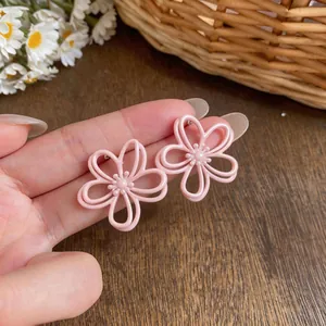 Primo piano di orecchini a fiore rosa traforati con delicata finitura smalto.