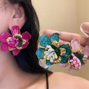 Primo piano di grandi orecchini a fiore in smalto colorato in stile bohémien dorato