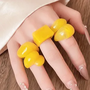 Close-up of yellow marbled chunky resin rings on a hand with decorative nails