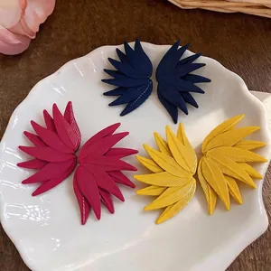 Stylish leaf pattern stud earrings in blue pink and yellow colors on a shell plate
