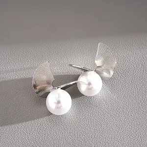 Detailed macro view of geometric silver fan-shaped earrings with large white pearls.