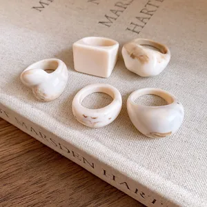 Detailed view of five vintage resin rings with brown marbled texture on linen book