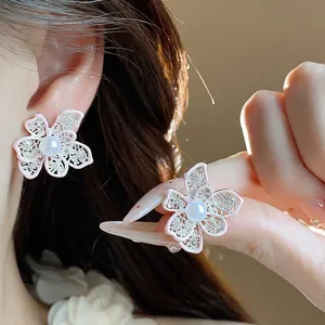 Eleganti orecchini a perno a fiore traforato con bordi in smalto rosa indossati da modella