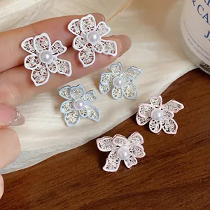 Eleganti orecchini a fiore traforati con perla centrale in tre colori pastello.