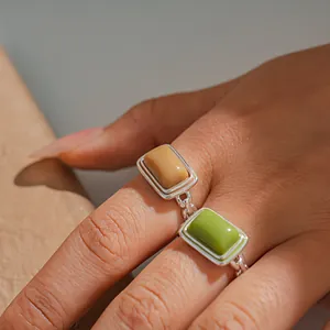 Close-up of green and beige resin rings with silver finish on hand model.