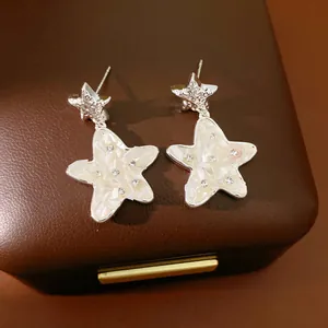 Primo piano di orecchini a stella in argento con intarsio in conchiglia e strass