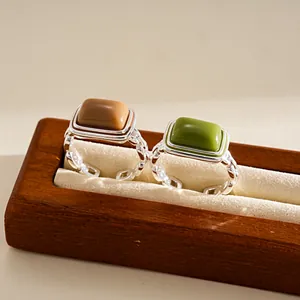 Detailed view of geometric square resin rings in brown and green on a wooden display